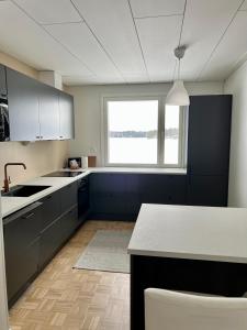 a kitchen with black and white cabinets and a window at Kotirinne 135 - järven rannalla in Jyväskylä