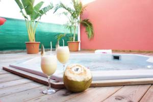een hot tub met 2 glazen champagne en een kokosnoot bij Gites de Bois d'Inde in Saint-François