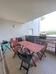 a picnic table and chairs on a balcony with a view at Bel appartement entre terre et mer in Sarrola-Carcopino