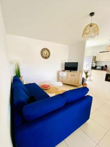 a blue couch in a living room with a table at Bel appartement entre terre et mer in Sarrola-Carcopino