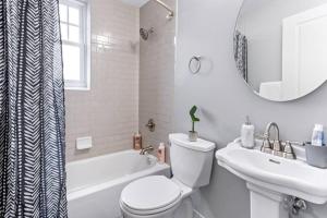 Baño blanco con aseo y lavamanos en Your Cozy One Bedroom Midtown, en Detroit