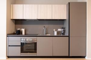 una cucina con armadi bianchi, lavandino e piano cottura di Daplace - Portaluppi Apartment a Milano