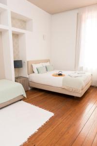a white bedroom with a bed and a wooden floor at Santo da Casa / Sc apartments in Porto