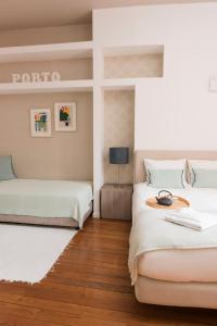 two beds in a room with wooden floors at Santo da Casa / Sc apartments in Porto