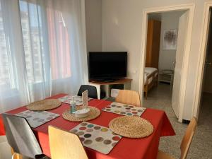 a dining room with a red table with chairs and a television at Sunny and Quiet Sagrada Familia in Barcelona