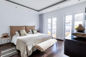 um quarto branco com uma cama grande e janelas em Fab's House em Faro