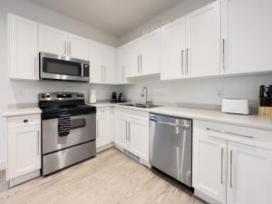 uma cozinha com armários brancos e electrodomésticos de aço inoxidável em New 1 bed, 1 bath king suite 3 min from beach em Surrey