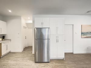 um frigorífico de aço inoxidável numa cozinha com armários brancos em New 1 bed, 1 bath king suite 3 min from beach em Surrey