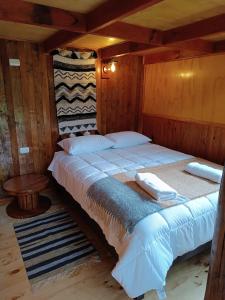 een groot bed in een kamer met houten wanden bij Cumbres del poicas in Cochamó