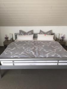 sypialnia z dużym łóżkiem z szarą pościelą i poduszkami w obiekcie Pension Ulrich w mieście Dahlem