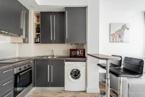 a kitchen with black cabinets and a washer and dryer at Precioso apartamento en el Barrio Salamanca P A D in Madrid