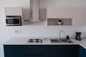 a white kitchen with a sink and a microwave at Departamento Vista Nova Culiacán in Casas