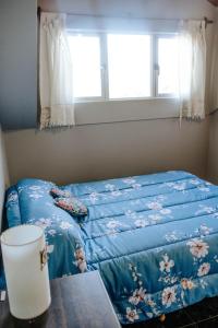 een slaapkamer met een bed met een blauwe deken en een raam bij Departamentos KAYLU in El Bolsón