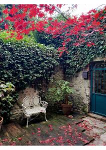un banco blanco sentado frente a una pared con flores rojas en La Venelle Saint Jean, en Honfleur