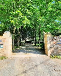 Zugang zu einer Einfahrt mit Bäumen und einer Steinmauer in der Unterkunft Le Gîte du Petit Plessis in Saint-Viaud
