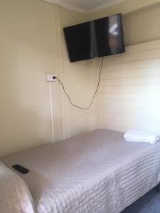 Habitación con cama y TV de pantalla plana en la pared. en Hospedaje 2174, en Iquique