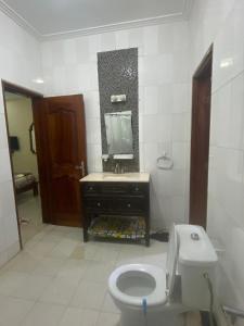 uma casa de banho com um WC, um lavatório e um espelho. em Appartement Ngor Almadie em Dakar