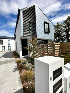 a white and black house with a wooden fence at Gem in Papanui Christchurch in Christchurch