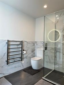 a bathroom with a toilet and a glass shower at Gem in Papanui Christchurch in Christchurch