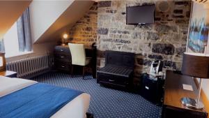 Habitación de hotel con cama y pared de piedra en Hotel Louisbourg en Quebec