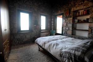 a bedroom with a bed in a room with windows at Stone house with panoramic view in Tyros