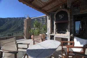 a patio with a table and chairs and a fireplace at Stone house with panoramic view in Tyros