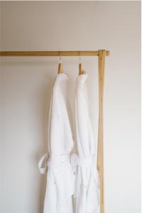 2 robes de mariage blanches suspendues sur un portant en bois dans l'établissement Brut the lodges, à Reijmerstok