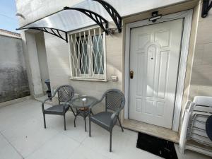 patio con mesa, sillas y puerta blanca en TheMaki'sHouse, en Fiumicino
