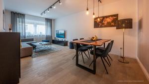 a dining room and living room with a table and chairs at FLAIR: stylisches Apartment - Netflix - BASF - Uni Mannheim in Ludwigshafen am Rhein