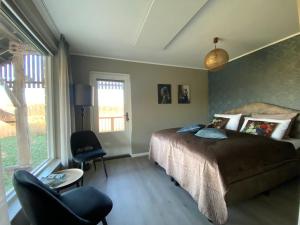 een slaapkamer met een bed, een stoel en een raam bij Landgoed Julianahoeve in Helenaveen