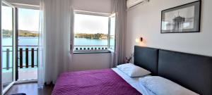 um quarto com uma cama com uma colcha roxa e 2 janelas em Pansion Alen - Dugi otok em Luka