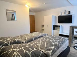 a bedroom with a bed and a flat screen tv at Gästehaus Ehebachhof Hotel Garni in Müllheim