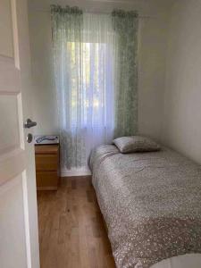 um pequeno quarto com uma cama e uma janela em Trevlig stuga med uteplats em Rimbo