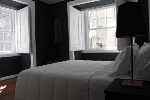 um quarto com uma cama branca e 2 janelas em Largo da Sé Guest House - HOrigem em Lisboa