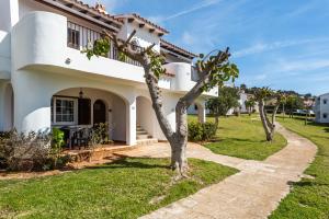 a white house with a tree in the yard at Apartamento Menorca SON BOU 53 by Mauter Villas in Son Bou