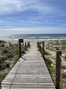 un chemin en bois menant à une plage avec l'océan dans l'établissement Apartamento Menorca SON BOU 53 by Mauter Villas, à Son Bou