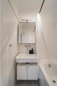 een witte badkamer met een wastafel en een bad bij Homely apartment - 10 minutes to Stephansplatz in Wenen