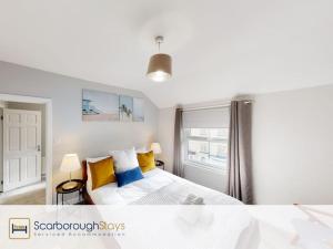 a bedroom with a bed with yellow and blue pillows at Scarborough Stays - Norwood House in Scarborough