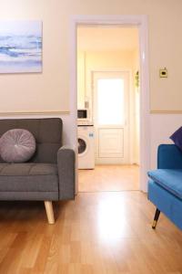 a living room with a couch and a blue chair at Unique 3 Bedroom House FREE WiFI & Parking in Knowsthorpe