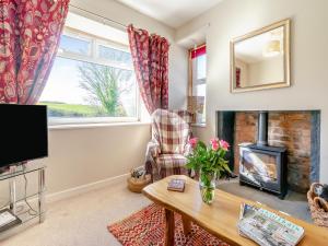 a living room with a fireplace and a tv at The Old Shepherds Cottage in Pitlessie