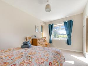 a bedroom with a bed with blue curtains and a window at The Old Shepherds Cottage in Pitlessie