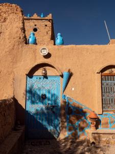 a blue door in the side of a building with graffiti at Chambres dans casbah - Gite D'étape Gorges De Ziz in Er Rachidia