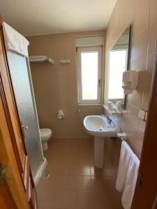 a bathroom with a sink and a toilet and a mirror at Hotel Chiquín in Tapia de Casariego
