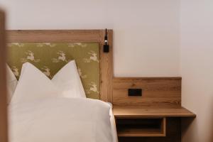 Appartement Steinerhof في فيرفينفينغ: سرير بمخدات بيضاء وطاولة خشب للرأس