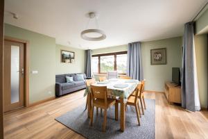 ein Wohnzimmer mit einem Tisch, Stühlen und einem Sofa in der Unterkunft Apartament Albatros 75m z ogródkiem in Warschau