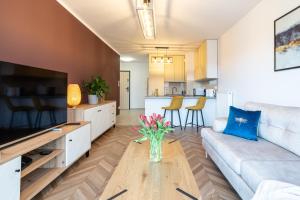 una sala de estar con sofá y un jarrón de flores sobre una mesa en LOTTE Apartment - parking podziemny, osiedle strzeżone, en Gliwice