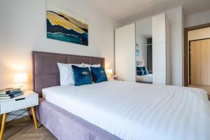 Un dormitorio con una gran cama blanca con almohadas azules. en LOTTE Apartment - parking podziemny, osiedle strzeżone, en Gliwice