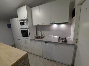 a small kitchen with white cabinets and a sink at Apartman Ana in Štinjan