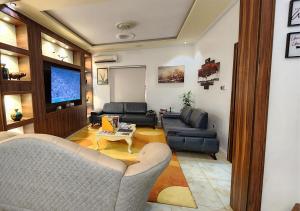 a living room with couches and a flat screen tv at Captain's Residence in Abuja