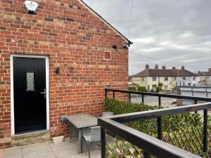 um edifício de tijolos com uma porta preta e um banco em Holdsworth House Apartments em Killingbeck